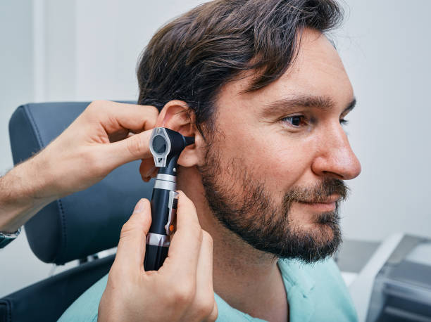 hombre adulto durante el examen del oído en la clínica de audición. audiólogo examinando el oído del paciente masculino usando otoscopio, primer plano - otoscopio fotografías e imágenes de stock