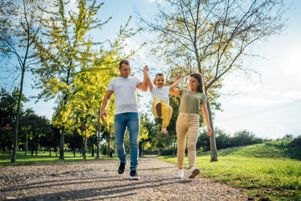 Happy family enjoying in the park Young happy family enjoying together in the park on summer day young family stock pictures, royalty-free photos & images