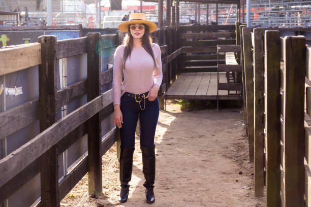Girl in hat working on farm smiling at camera.