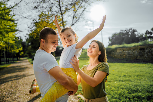 Young happy family together in the park on sunny summer day