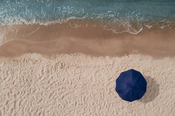 istock Beach umbrella on sandy coast near sea, top view 1427988280