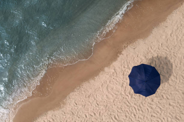 istock Beach umbrella on sandy coast near sea, top view 1427988311