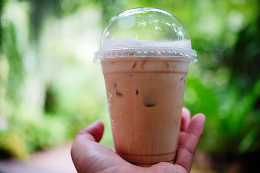 Close-up latte in disposable take away cup Iced on hand