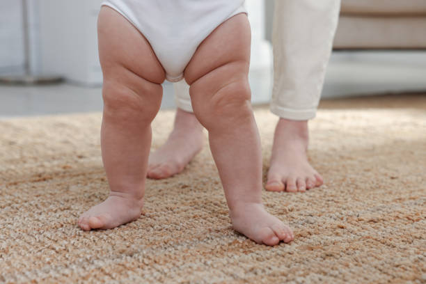 istock Cute little baby doing first steps with mother's help at home, closeup 1427991102