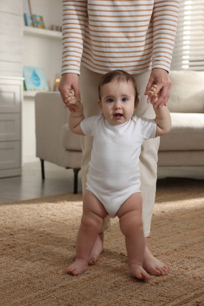 istock Cute little baby doing first steps with mother's help at home, closeup 1427991715