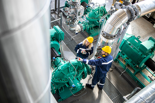 Trabajadores o ingenieros de la refinería que inspeccionan la funcionalidad de las tuberías de gas y los generadores. Industria petroquímica y producción de petróleo. photo