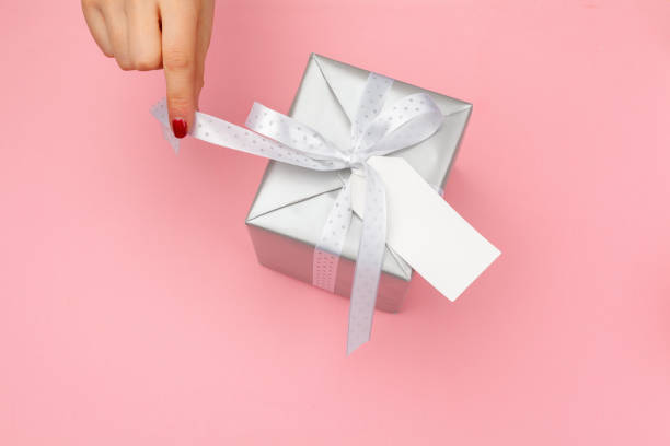 istock Woman holding gift box on color background 1428000440