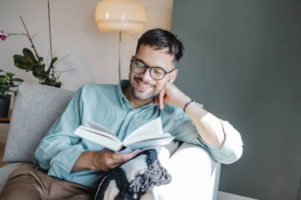 istock A young man reading a book in his living room 1428000783
