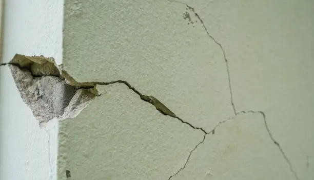 Photo of Old wall with white plaster and cracked peeling texture in black and white copy space. Grunge cracked concrete wall.