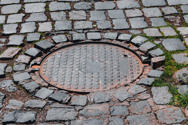 istock Round rusty metallic sewer cap on a paved road 1428008720