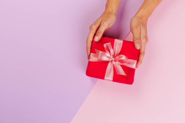 istock Woman holding gift box on color background 1428014181