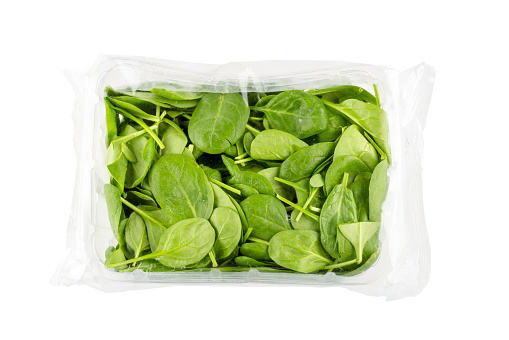 Baby spinach vegetable in plastic wrap - concept of plastic overuse and pollution