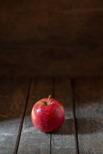 istock Red apple in water drops on wooden background texture 1428021207