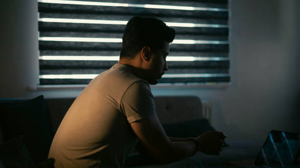 istock Thoughtful young man in low light. Dramatic concept , man sitting on sofa 1428021249