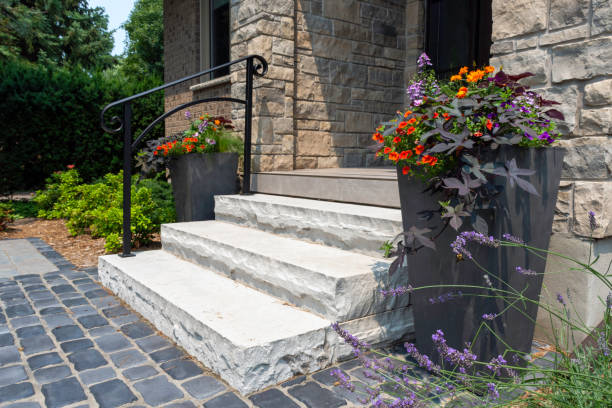 el detalle del paisaje duro residencial muestra escalones de piedra natural con barandilla de hierro negro, un rellano de adoquines y grandes jardineras. - florida house patio real estate fotografías e imágenes de stock