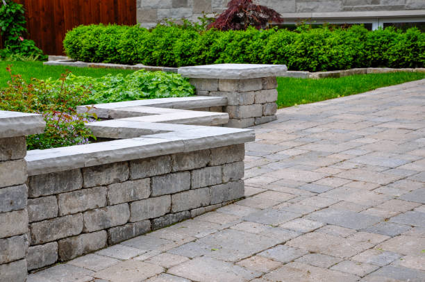 A tumbled paver retaining wall with natural stone coping defines a driveway.