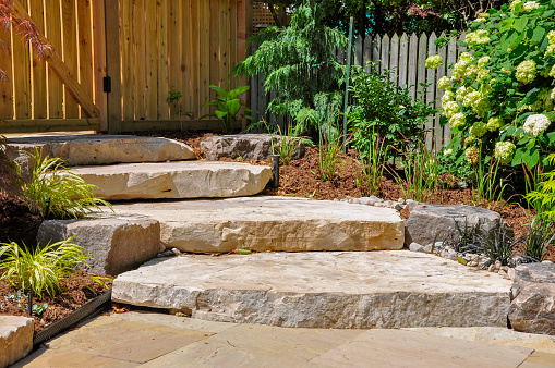 Huge natural stone slab steps create a beautiful landscape, and a transition to a hidden upper garden in this front yard urban garden.