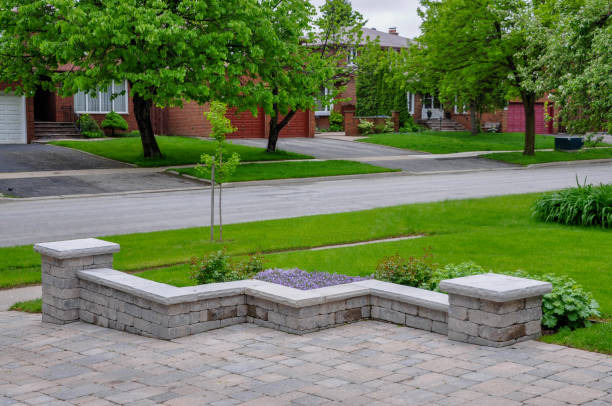 eine getrommelte pflasterstützmauer mit natursteinbelägen definiert eine einfahrt. - driveway patio stone footpath stock-fotos und bilder