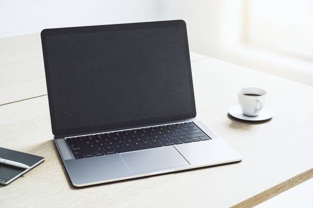 istock Perspective view on blank dark modern laptop screen with copyspace for your logo or text on light wooden table with coffee mug in sunny office area. 3D rendering, mockup 1428038331