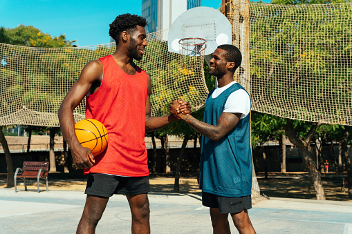 One vs one basketball game training at the court. Cinematic look image of friends practicing shots and slam dunks in an urban area