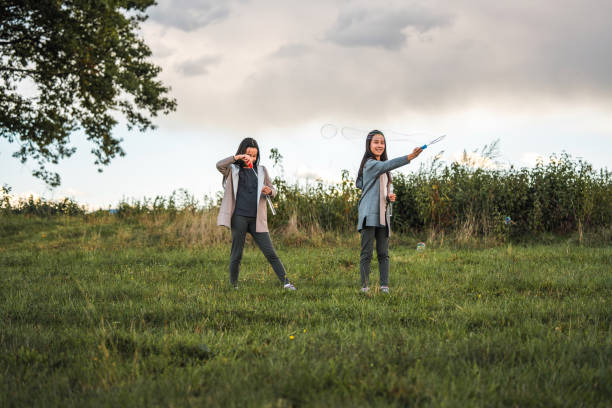 istock Female Twins Playing With Bubble Wands 1428049315