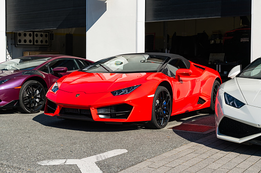 Three Lamborghini Huracans are parked at a Lamborghini dealership in Vancouver BC Canada on a sunny day