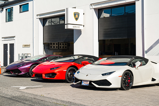 Three Lamborghini Huracans are parked at the service part of a Lamborghini dealership in Vancouver BC Canada on a sunny day