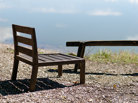 Close-up photo of a wooden chair on the lake shore