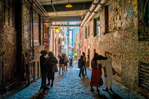 People take pictures at the famous Gum Wall on Post Alley in downtown Seattle, Washington, USA on a sunny day.