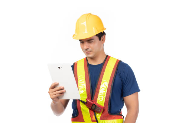 istock Construction handsome man worker in yellow helmet and reflective vest and using tablet for check work with team staff isolated on white background. 1428069986