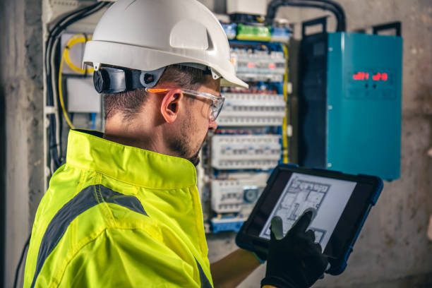 man, an electrical technician working in a switchboard with fuses, uses a tablet. - alleen één mid volwassen man fotos stockfoto's en -beelden