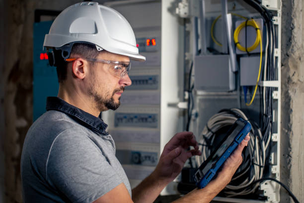 istock Man, an electrical technician working in a switchboard with fuses, uses a tablet. 1428072853