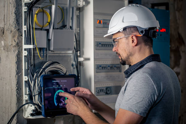 istock Man, an electrical technician working in a switchboard with fuses, uses a tablet. 1428072856