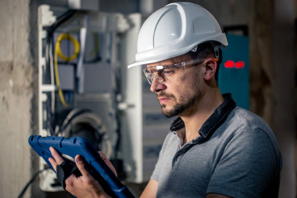 istock Man, an electrical technician working in a switchboard with fuses, uses a tablet. 1428072861