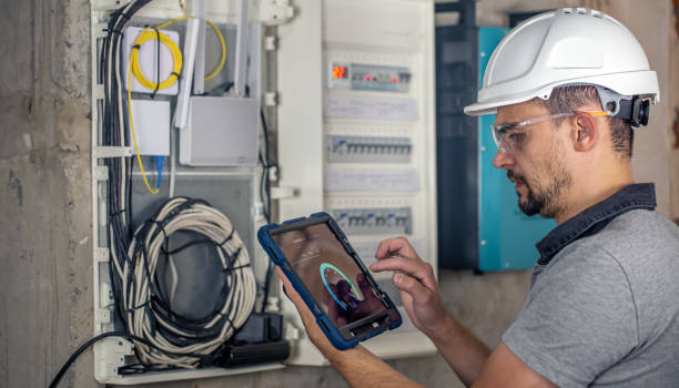 istock Man, an electrical technician working in a switchboard with fuses, uses a tablet. 1428072863
