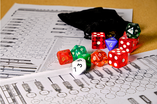 Several role-playing game dice with a role-playing character token, on top of a table.