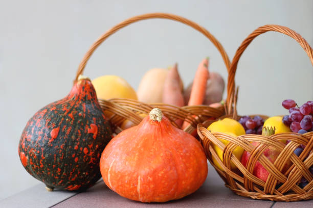 Hokkaido pumpkins and vintage baskets filled with various autumnal produce in the kitchen. Selective focus.