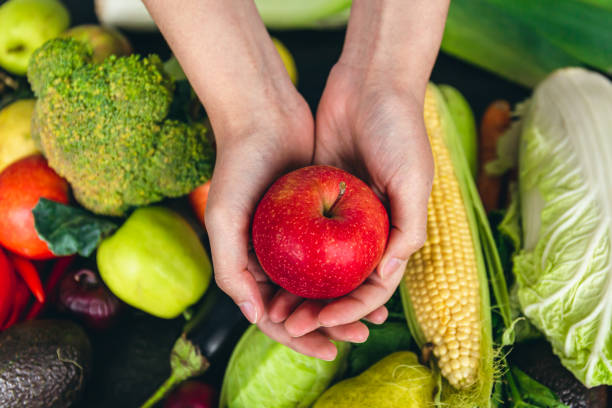 istock Close-up, an apple in a female hand on a blurred background with vegetables. 1428074157