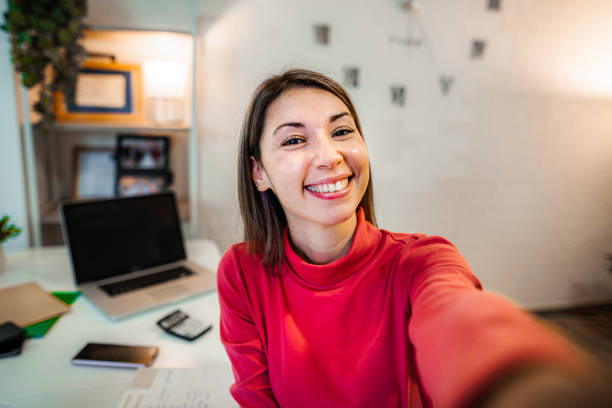 Self portrait of a smiling woman while working from home on her lap top