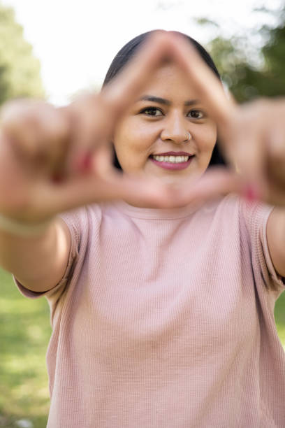 istock young woman in a park making a triangle with her hands while smiling, lifestyle and natural beauty 1428077820