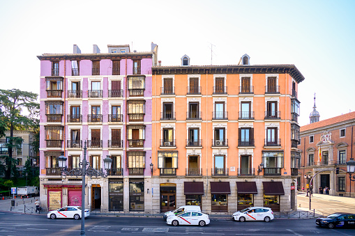 Madrid, Spain - September 15, 2022: Frontage of a five-story building on a street corner. There are cars on the street, and incidental people are walking in the scene.