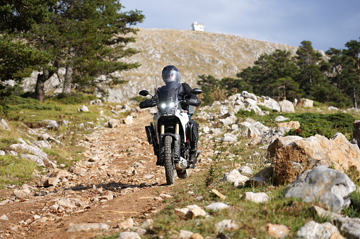 A man riding an off-road motorcycle on a mountain road