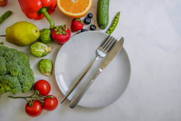 istock Plate fork knife vegetables and fruits on a light background 1428082264