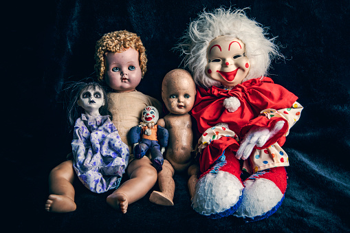 A collection of five creepy dolls photographed on a black background.