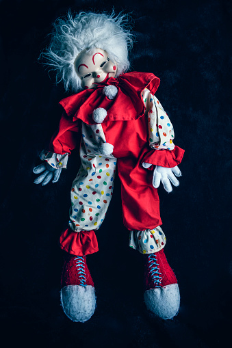 A sinister looking clown doll standing on it's toes.