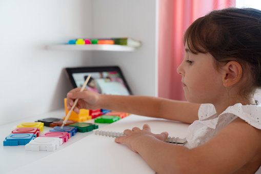 Little child girl painting with her watercolors with a brush. making a picture