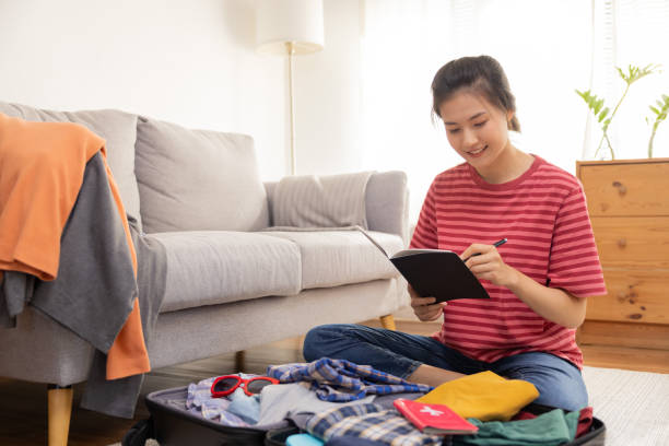 istock Asian Female Traveler Check Her List in a Note While Pack Her Suitcase 1428085477