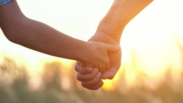 istock Son holds father hand against blurry sunset on evening sky 1428087083