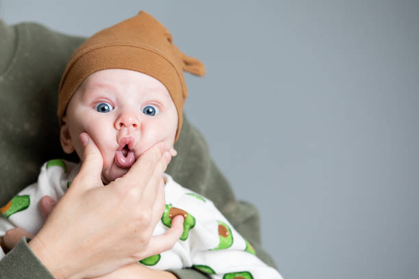 la madre aplasta las mejillas del bebé que lleva lindo onesie y sombrero - chubby cheeks fotografías e imágenes de stock