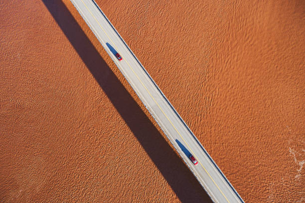 Aerial view of two cars on a rural highway crossing a tidal river.